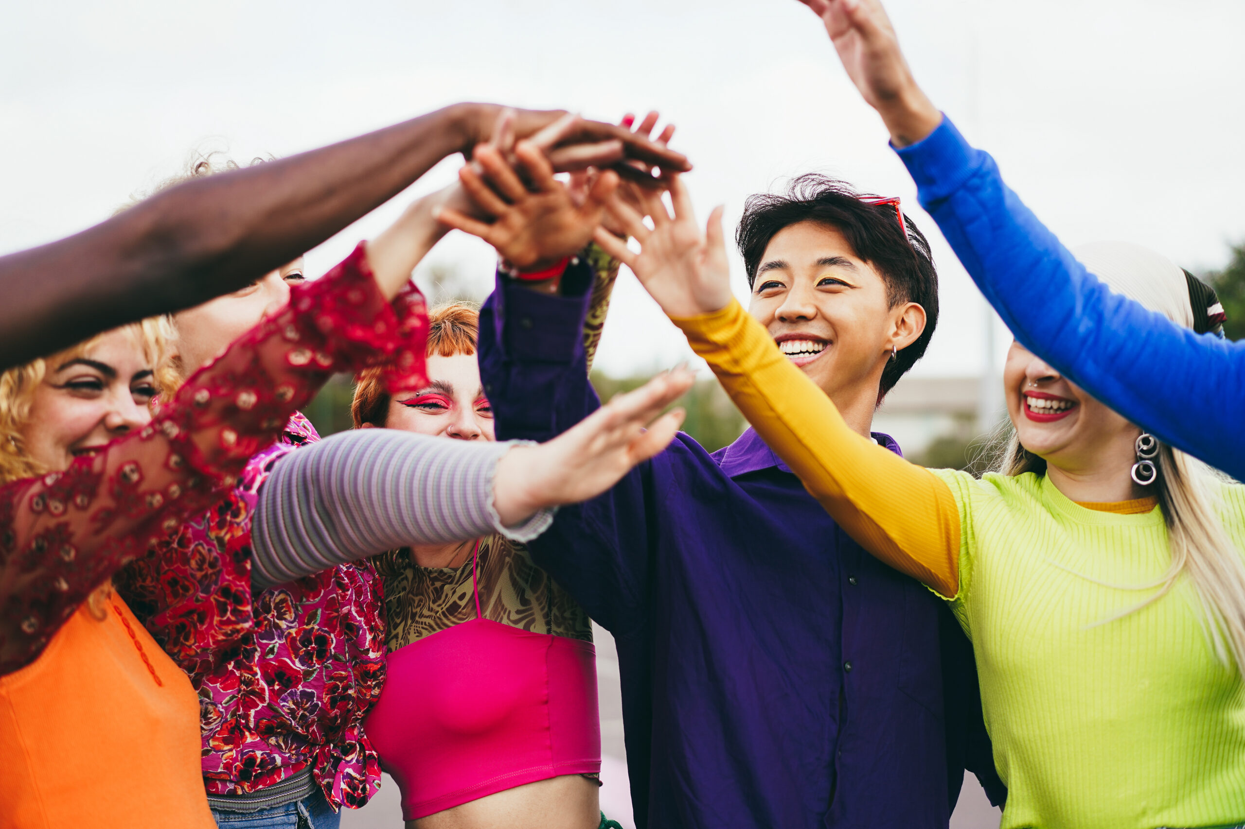 Young diverse friends having fun stacking hands outdoor - Focus on girl with pink eyeshadow